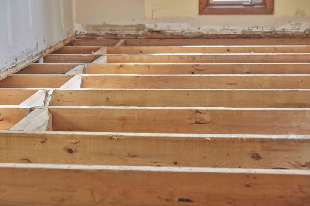 Exposed wooden floor joists in a home with the subfloor removed