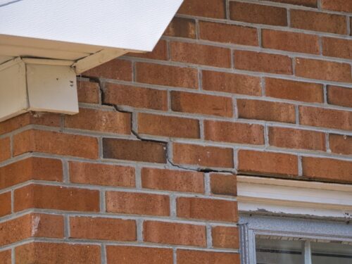 Diagonal crack running through the brick wall at the corner of a house